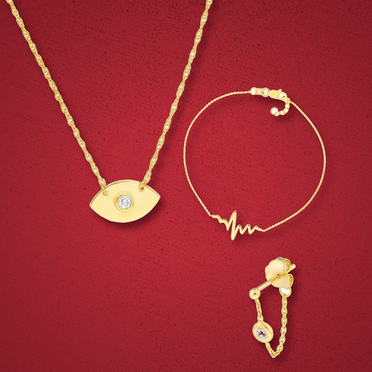 14K gold diamond evil eye necklace, heartbeat bracelet and diamond chain huggie on burgundy